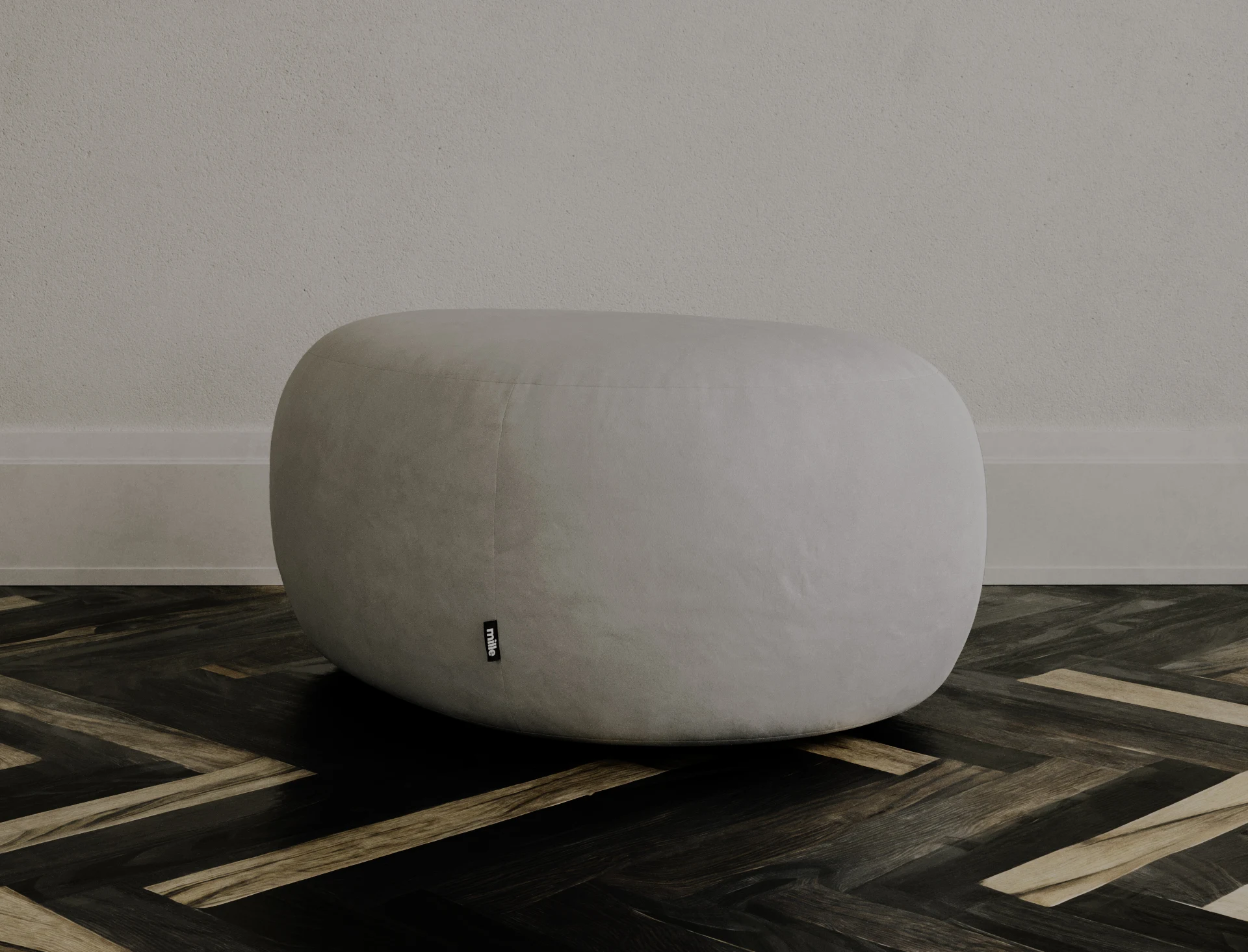 Grey velvet Chios pouf on a parquet floor showing the edgeless river-stone silhouette