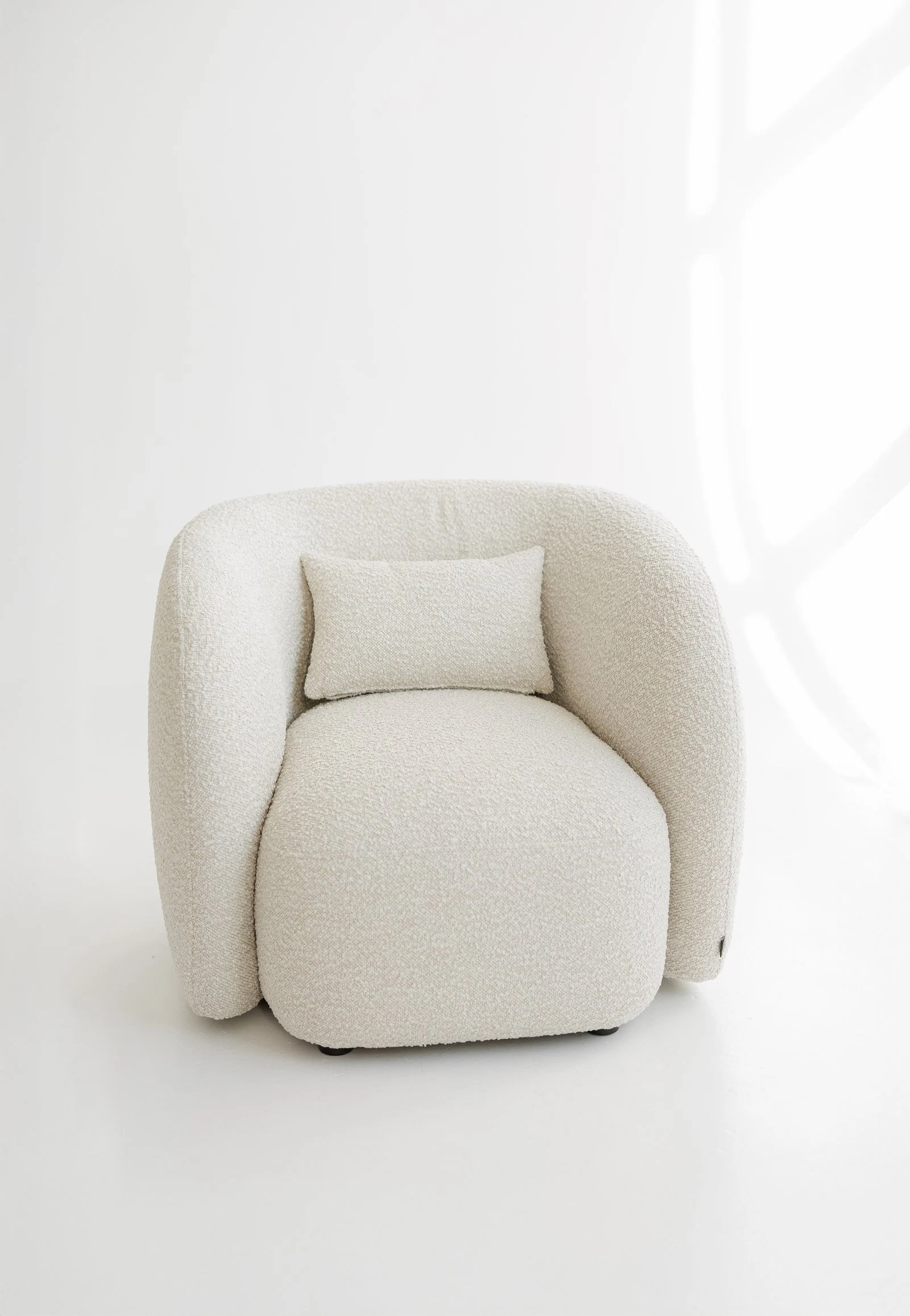 Cream Santa Cruz 801 boucle Nuba armchair photographed in a bright minimal studio with a back cushion in the seat