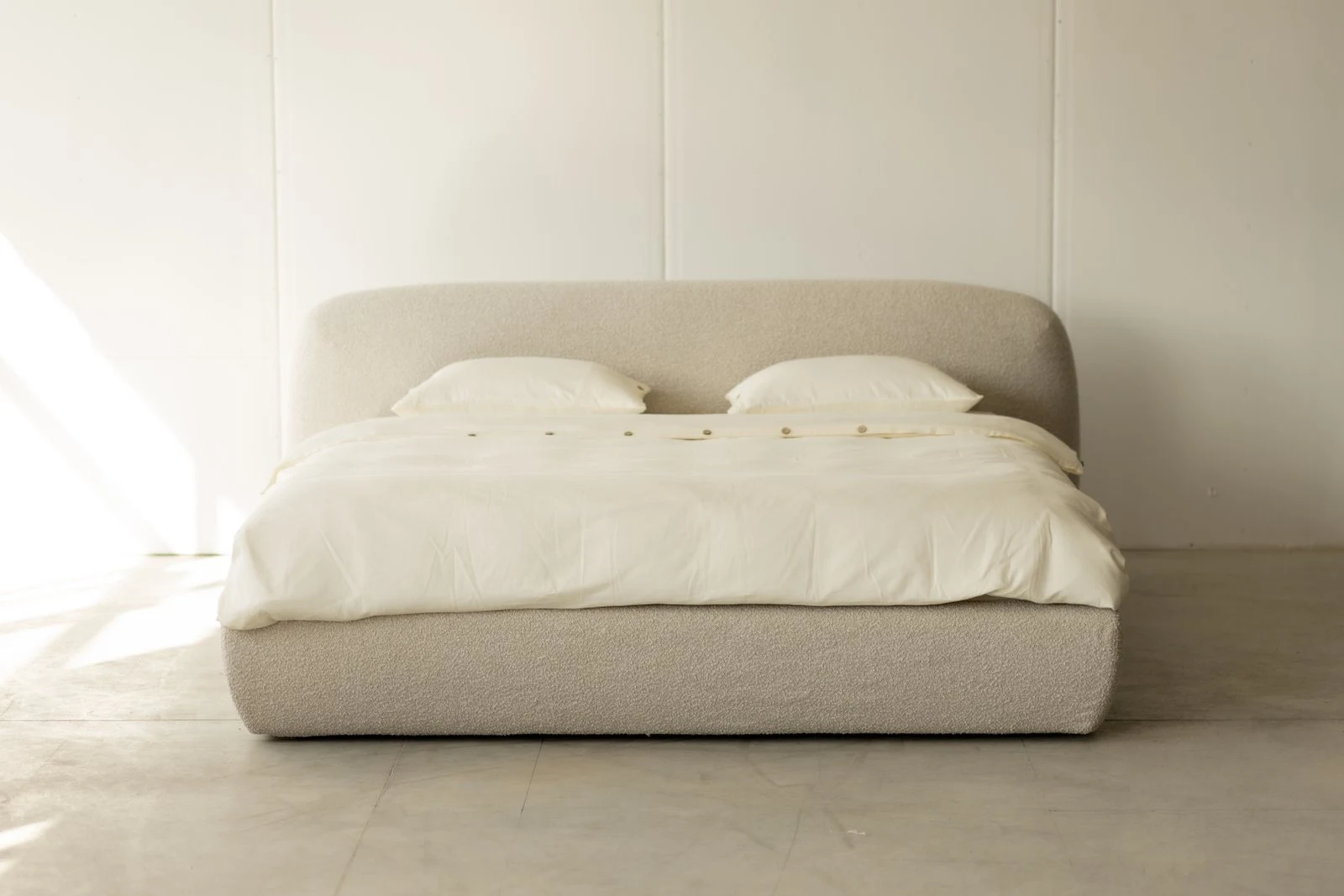 Cream boucle Belagio centered against a white panel-board wall, clean studio light