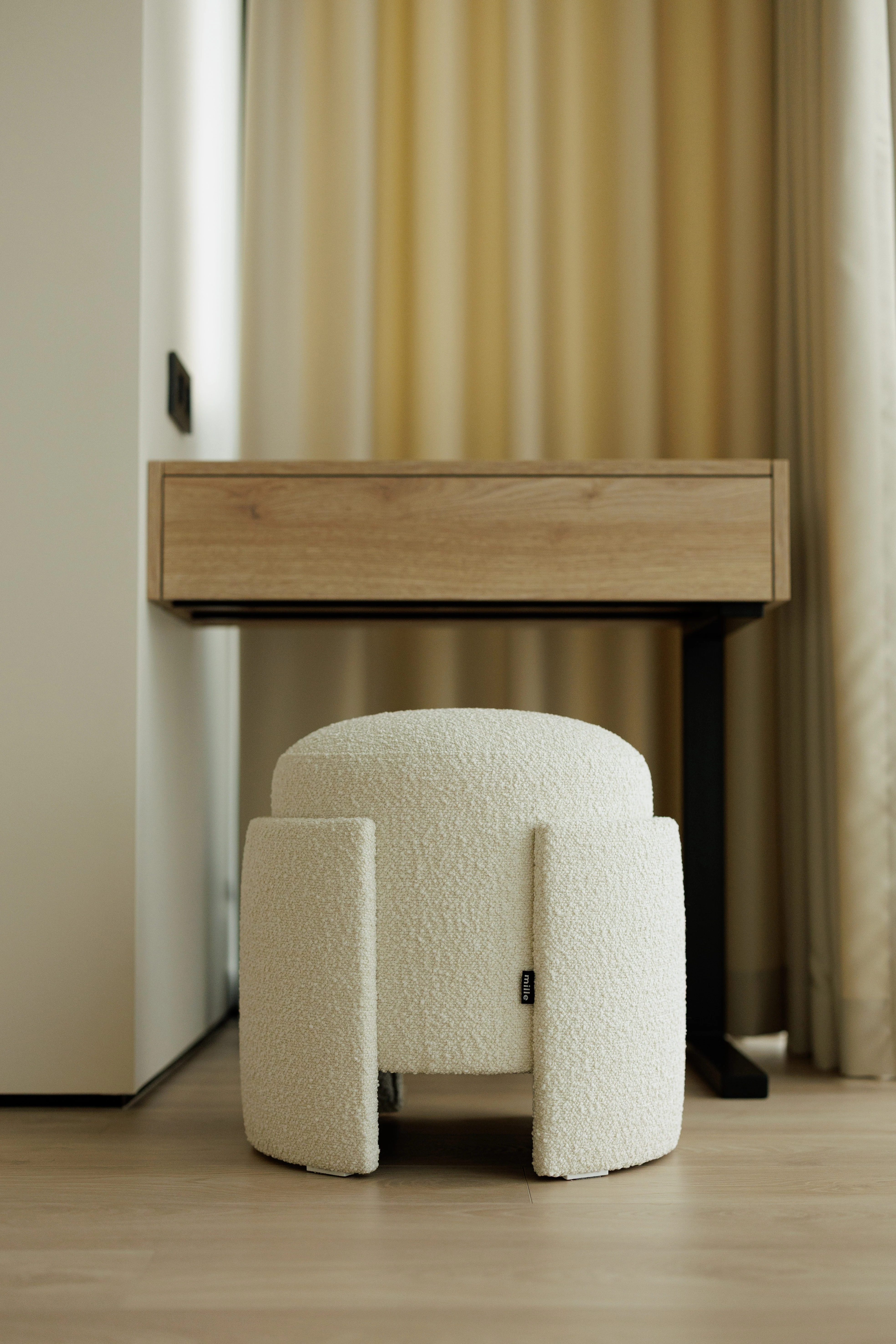 Cream bouclé Eden pouf seen from the front under a wood vanity desk