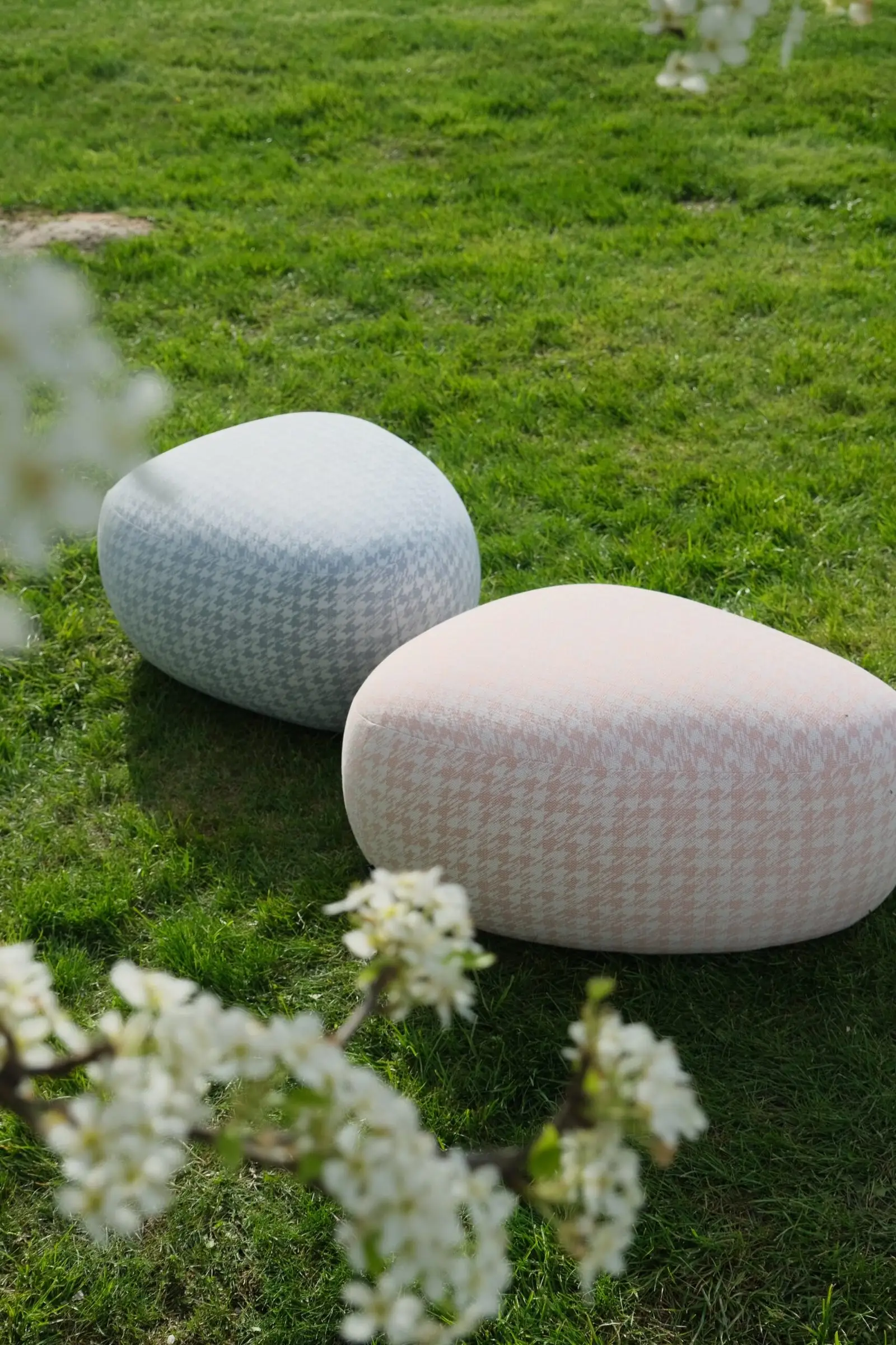 Pink and blue houndstooth Chios poufs in a grassy garden