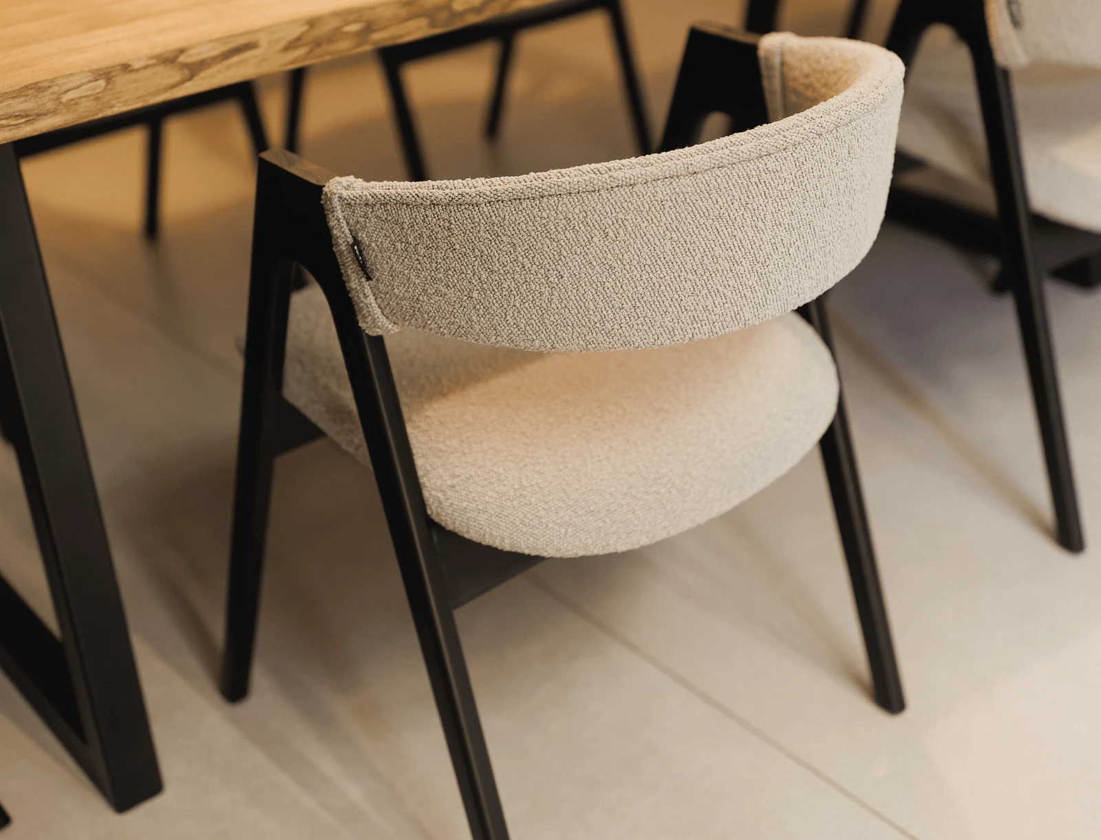 Cream boucle Lain chair on black-stained ash frame at a light wood dining table