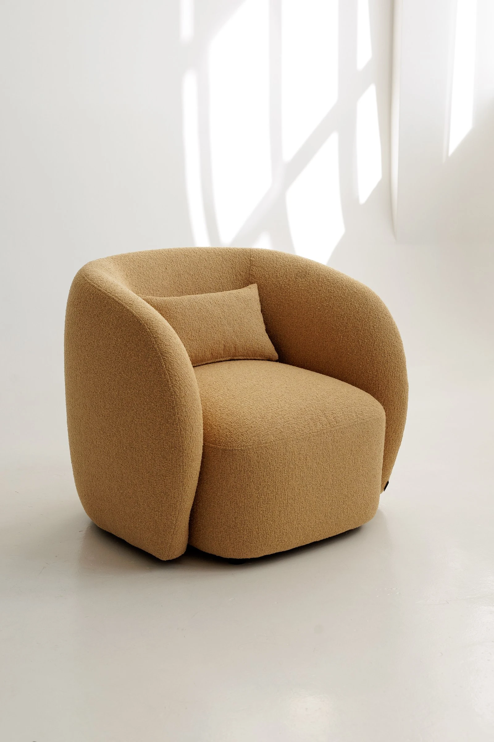 Mustard Everest 103 boucle Nuba armchair photographed in a bright studio with a loose back cushion