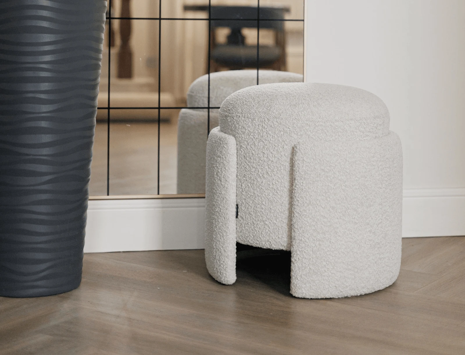 Eden pouf beside a dark ribbed vase and a mirror