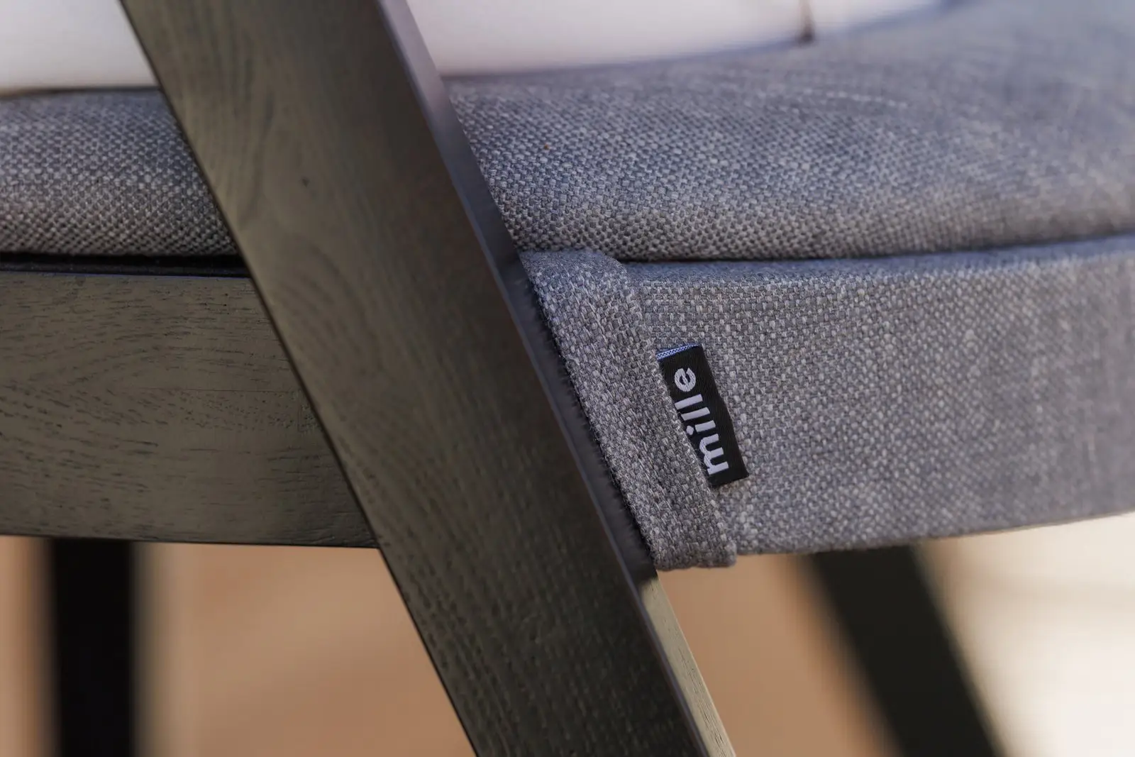 Close detail of the small Mille label sewn into the grey Antwerp seat of the Baffi bar stool