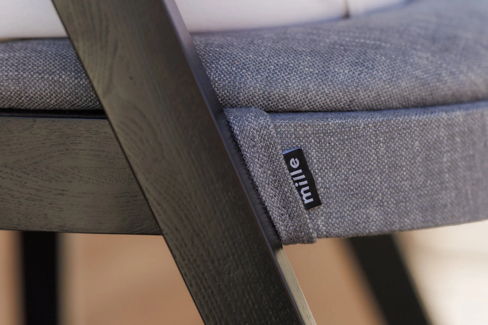 Close detail of the small Mille label sewn into the grey Antwerp seat of the Baffi bar stool