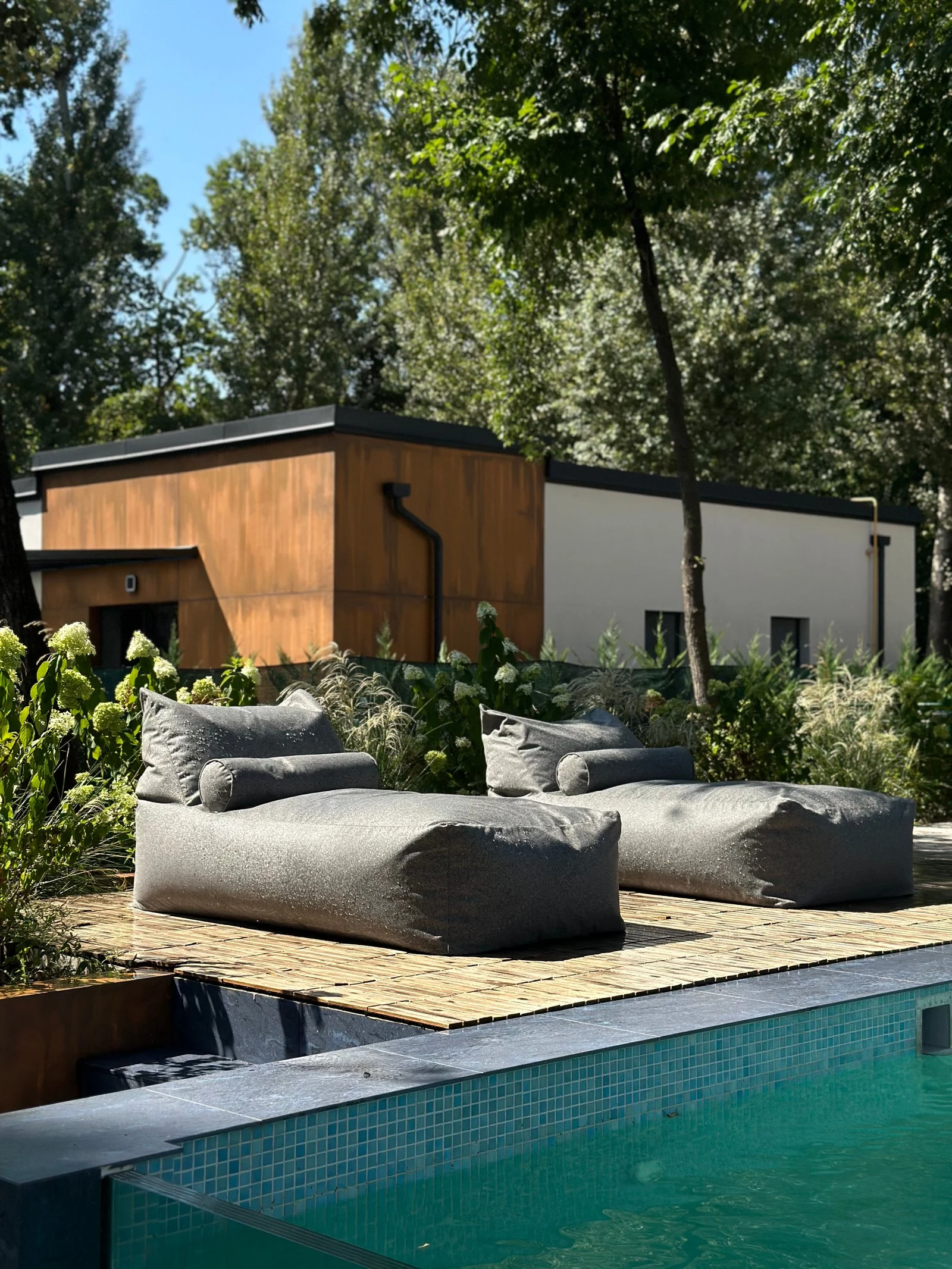 Two deep-grey Marolla loungers on a deck beside a villa pool