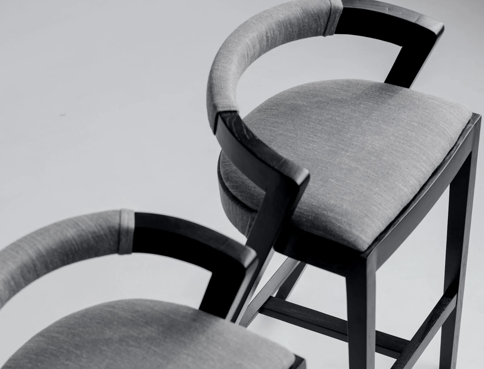 Three-quarter view of the Baffi bar stool in the studio showing the black ash frame and grey upholstered seat