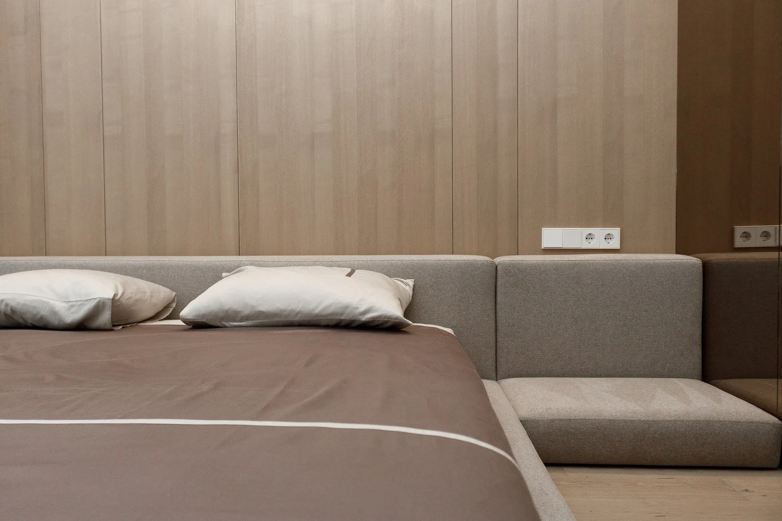 Close view of the Connect's back cushion modules against a wood-paneled wall with the bench extension visible at the foot