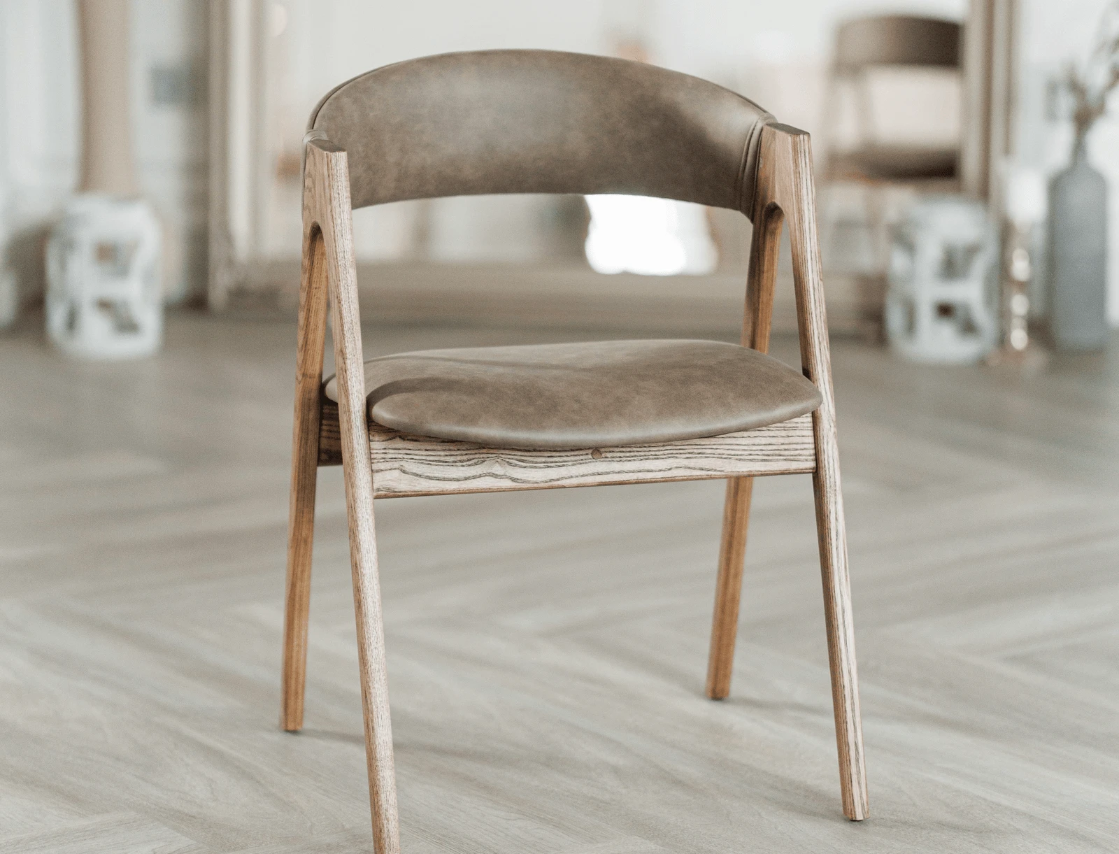 Three-quarter view of the coffee leather Lain chair near the mirror