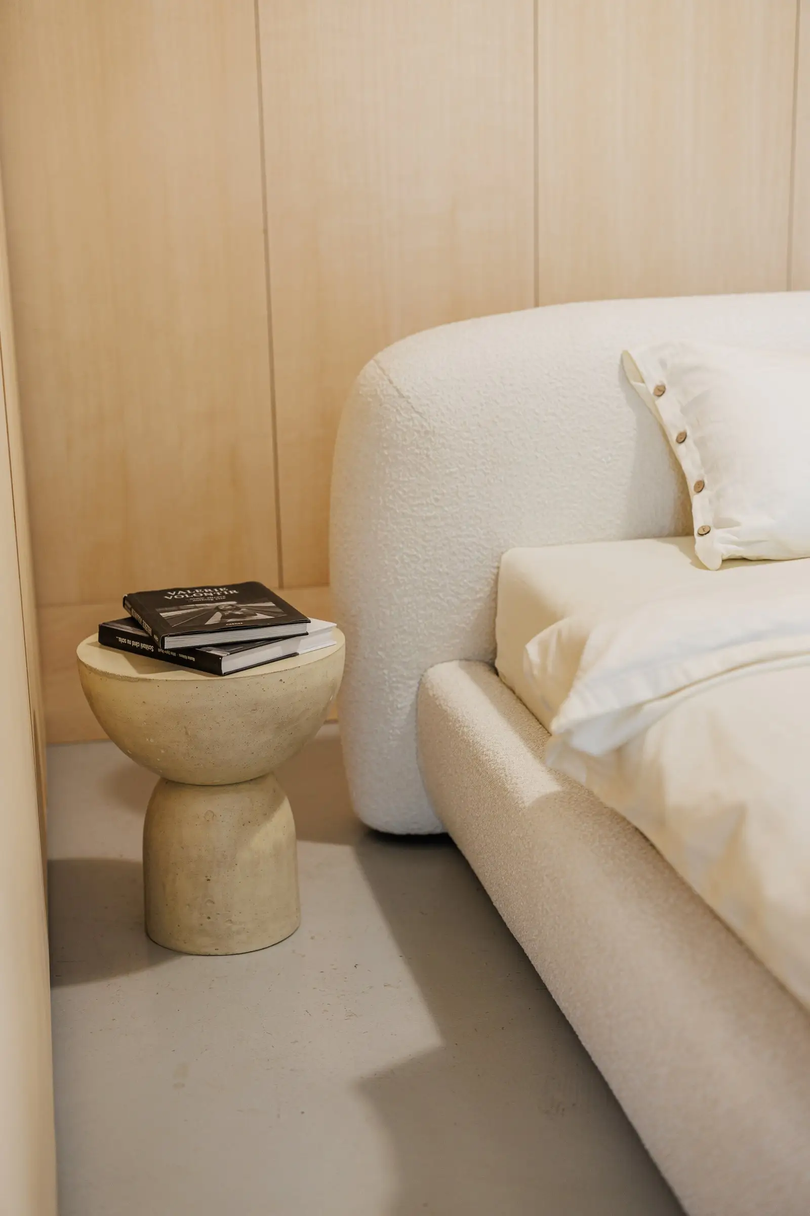Stone side table beside the Belagio holding two black design monographs, cream boucle in the frame