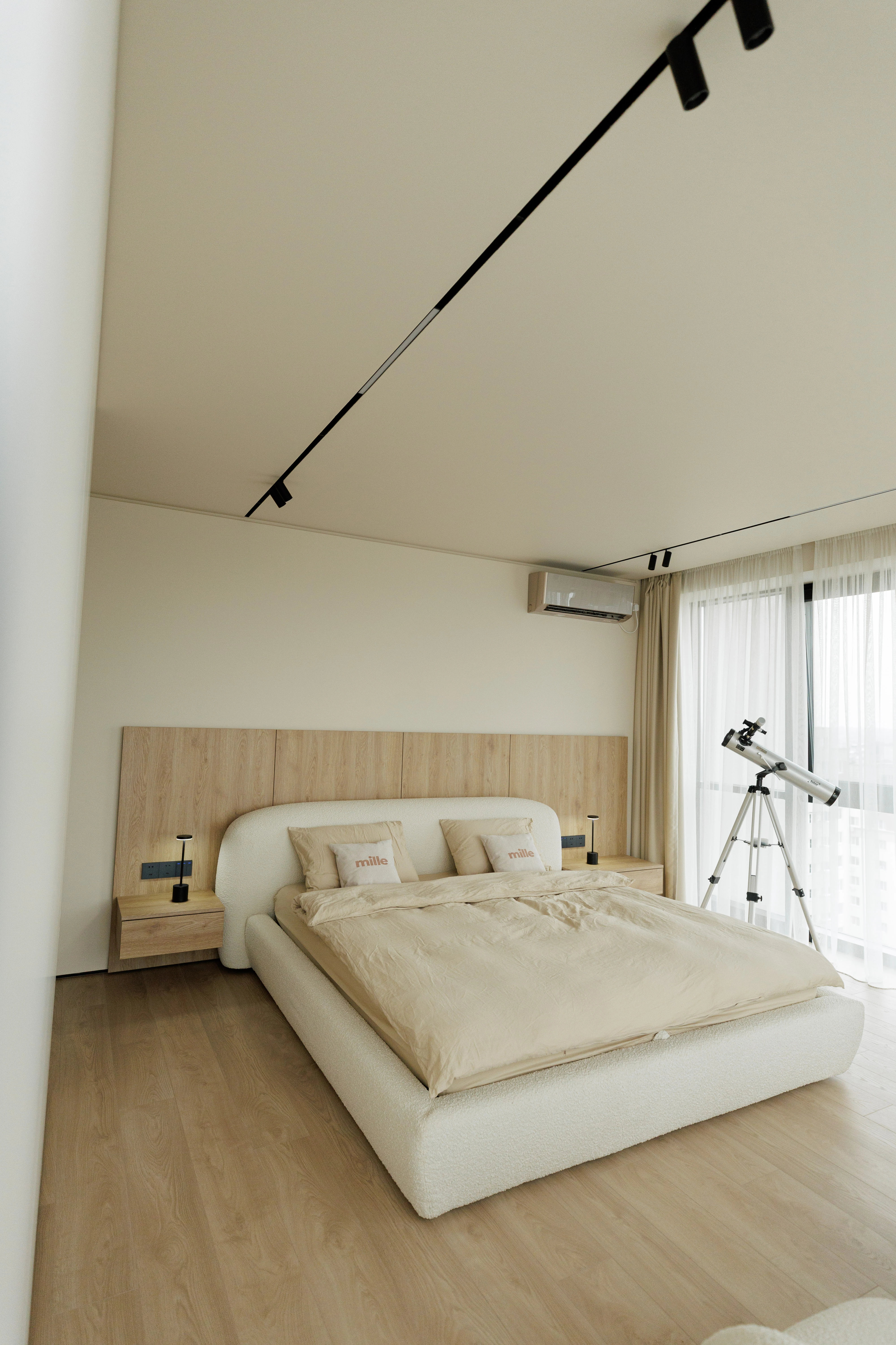 Cream boucle Belagio in a real apartment bedroom with light oak floor, a small telescope by the window, and a wood-paneled accent wall behind the bed