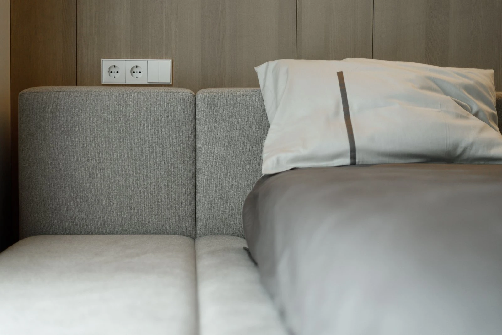 Detail of the Connect back-cushion sectional with electrical outlets mounted in the wood-paneled wall behind