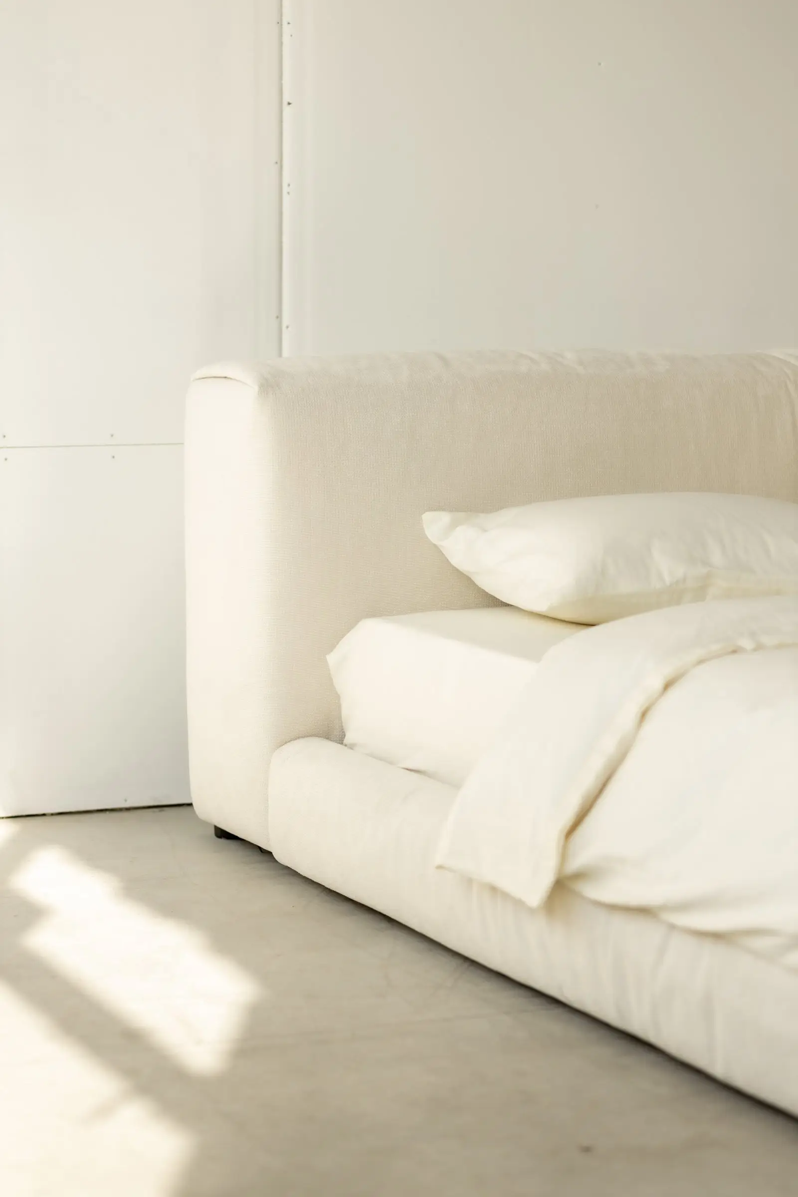 Close detail of the Marmaris headboard corner falling naturally at floor level with white bedding