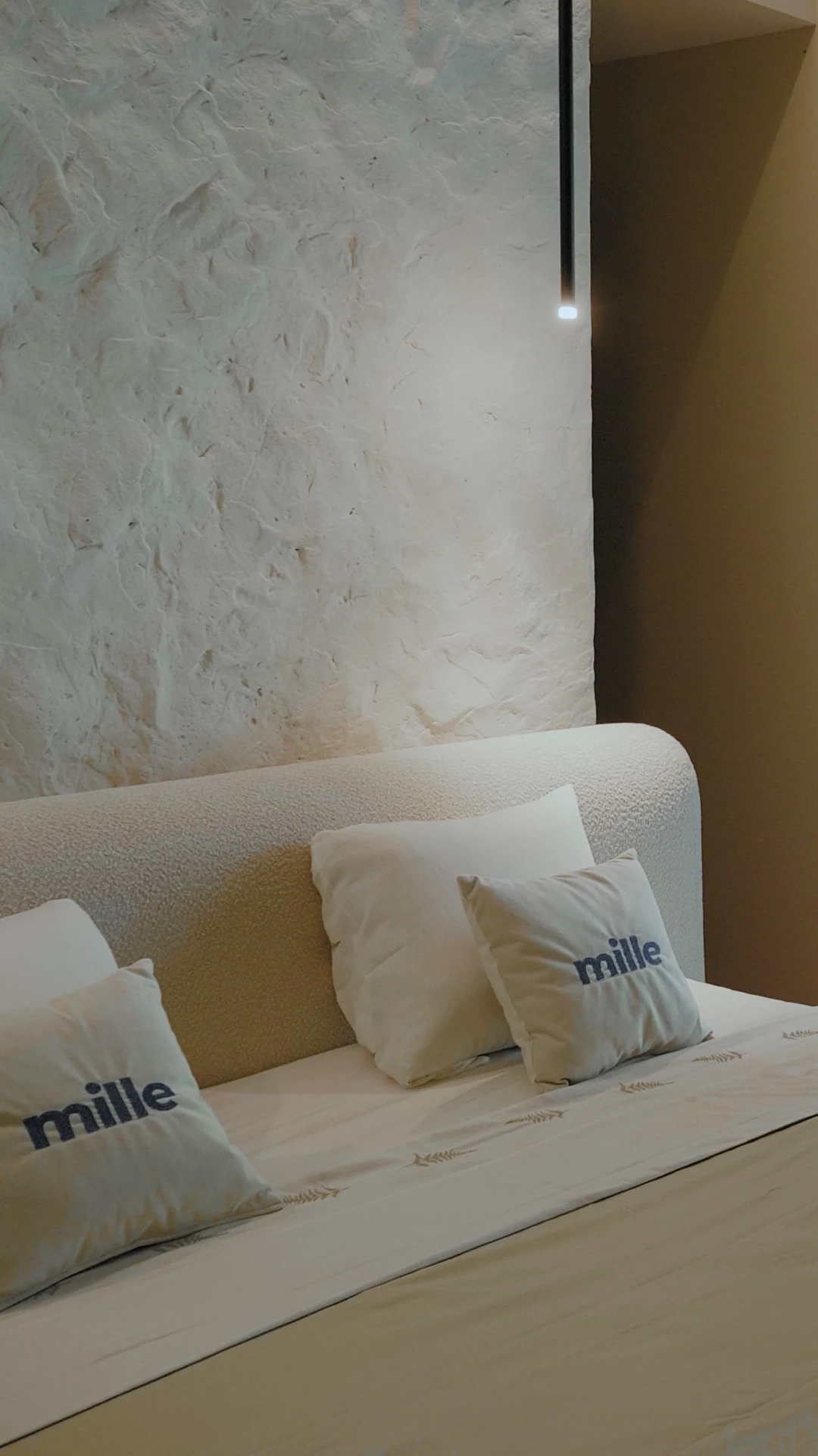 Close detail of the Fresco arched headboard against a textured plaster wall, showing the soft rounded top edge and the cream boucle weave