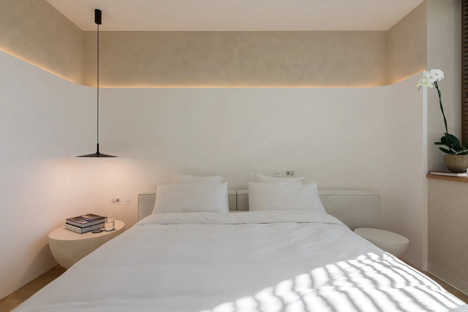 Cream Palermo centered in a light bedroom with twin pebble side tables and a single black pendant lamp