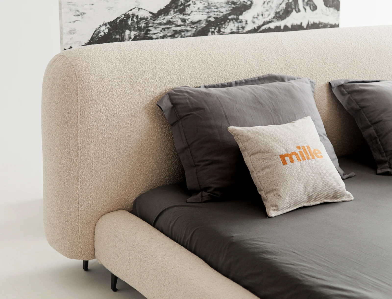 Close detail of a Mille-branded coral pillow resting in front of the sand boucle Fresco headboard