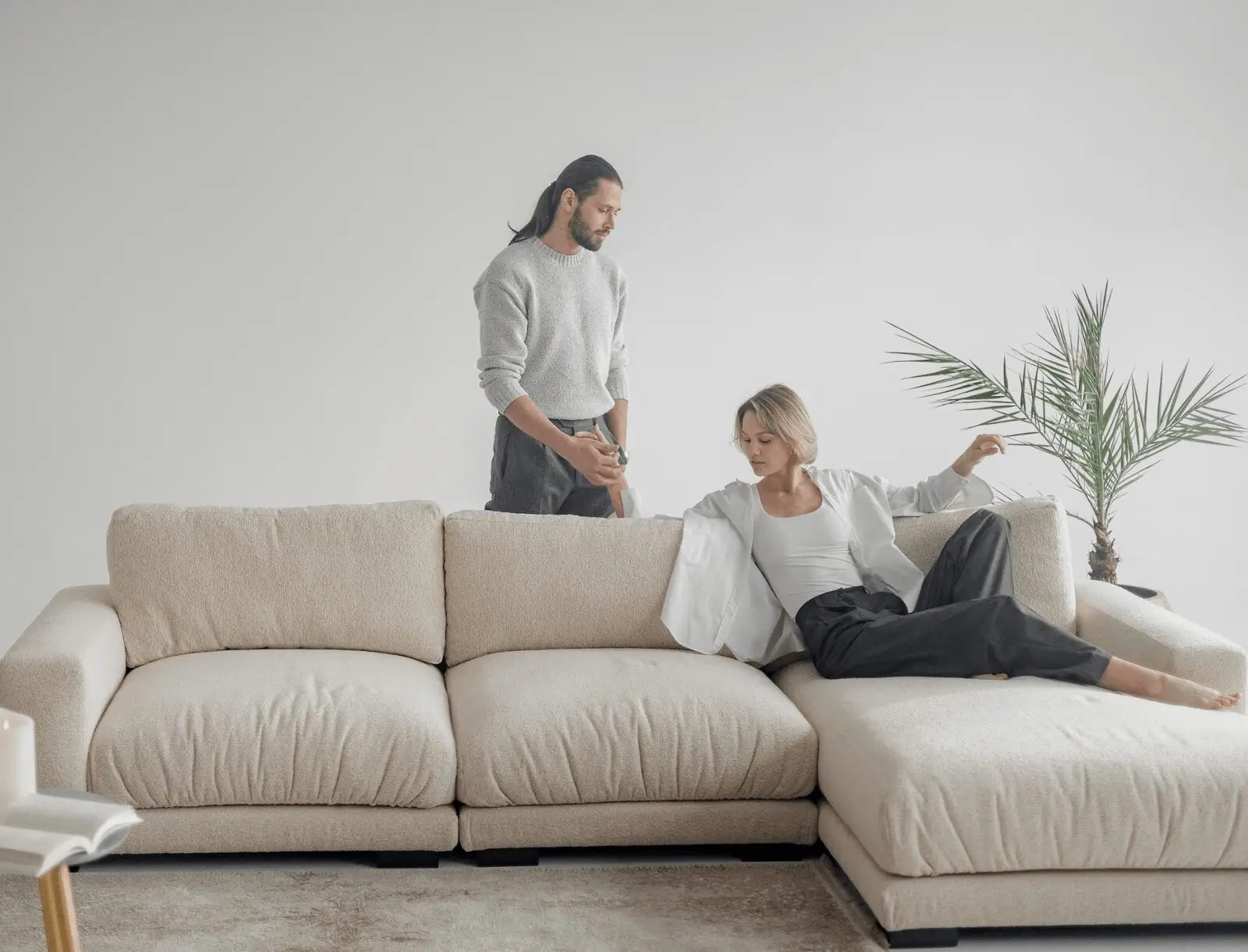 Couple on a cream Palermo sectional in a softly lit room, the model lounging on the chaise