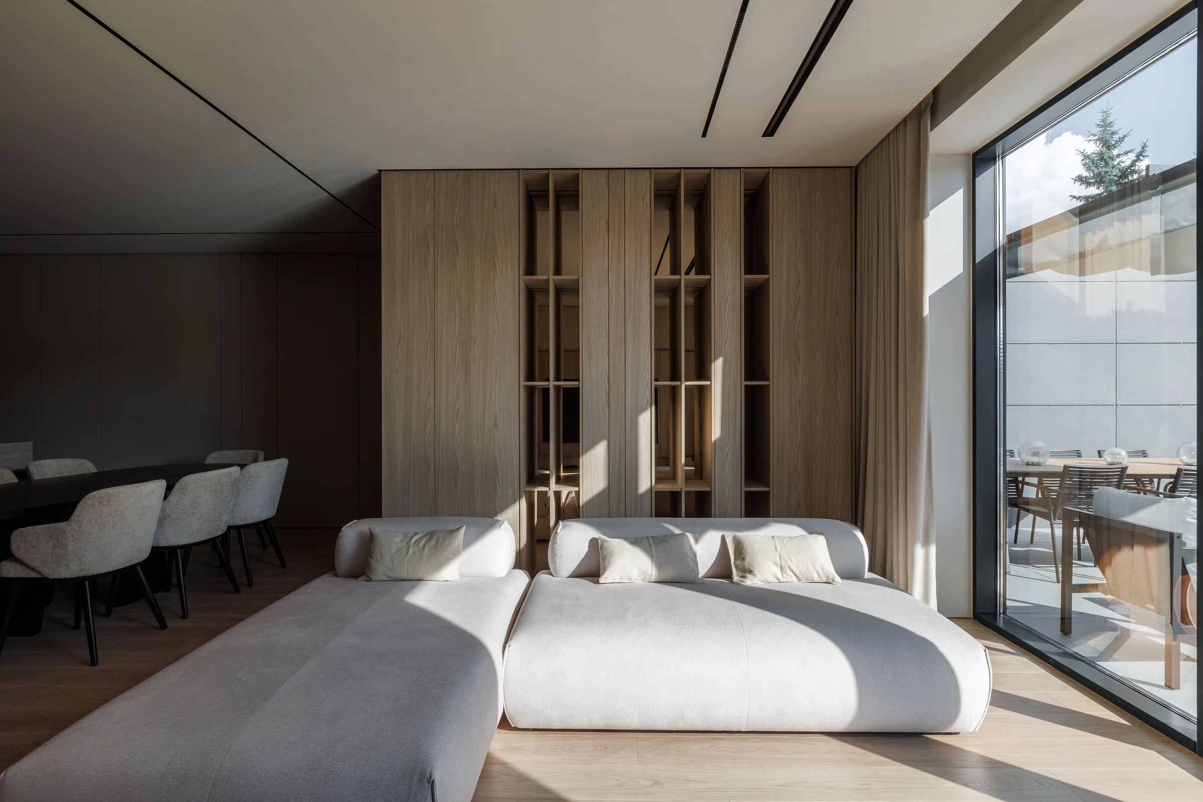 Cream Nissa sectional in a luxury apartment with oak slat walls, cream pillows, and a garden view through tall windows