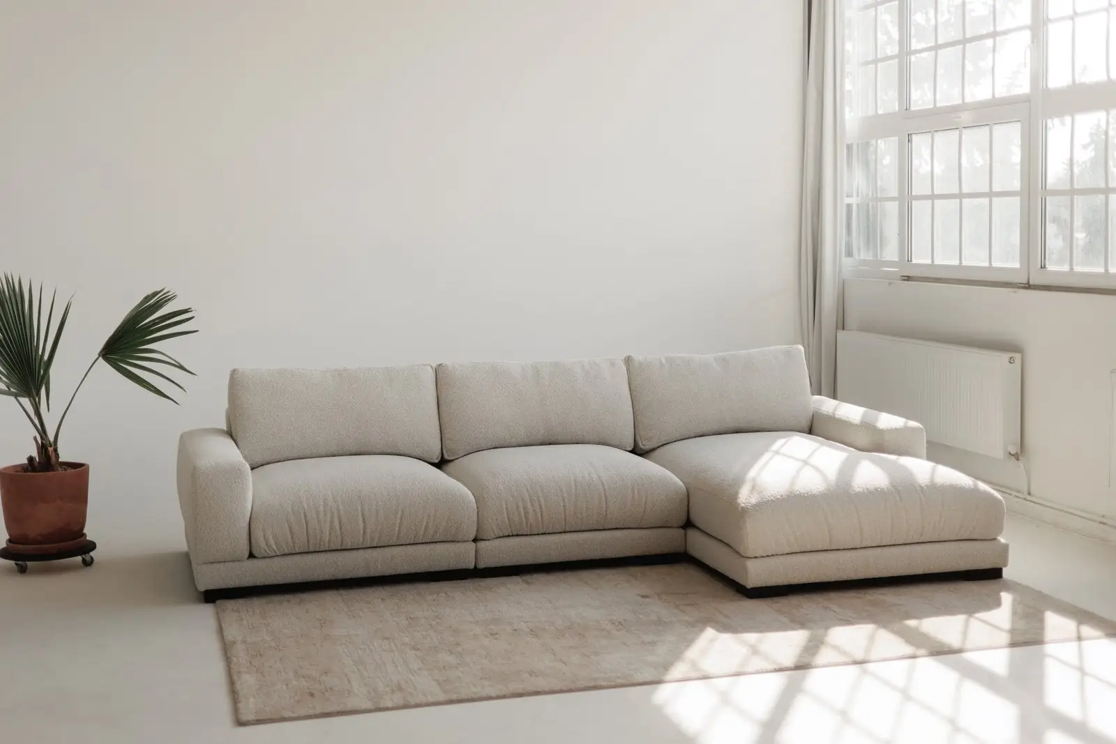 Cream Palermo sectional in a sunny studio with industrial grid windows and oak rug