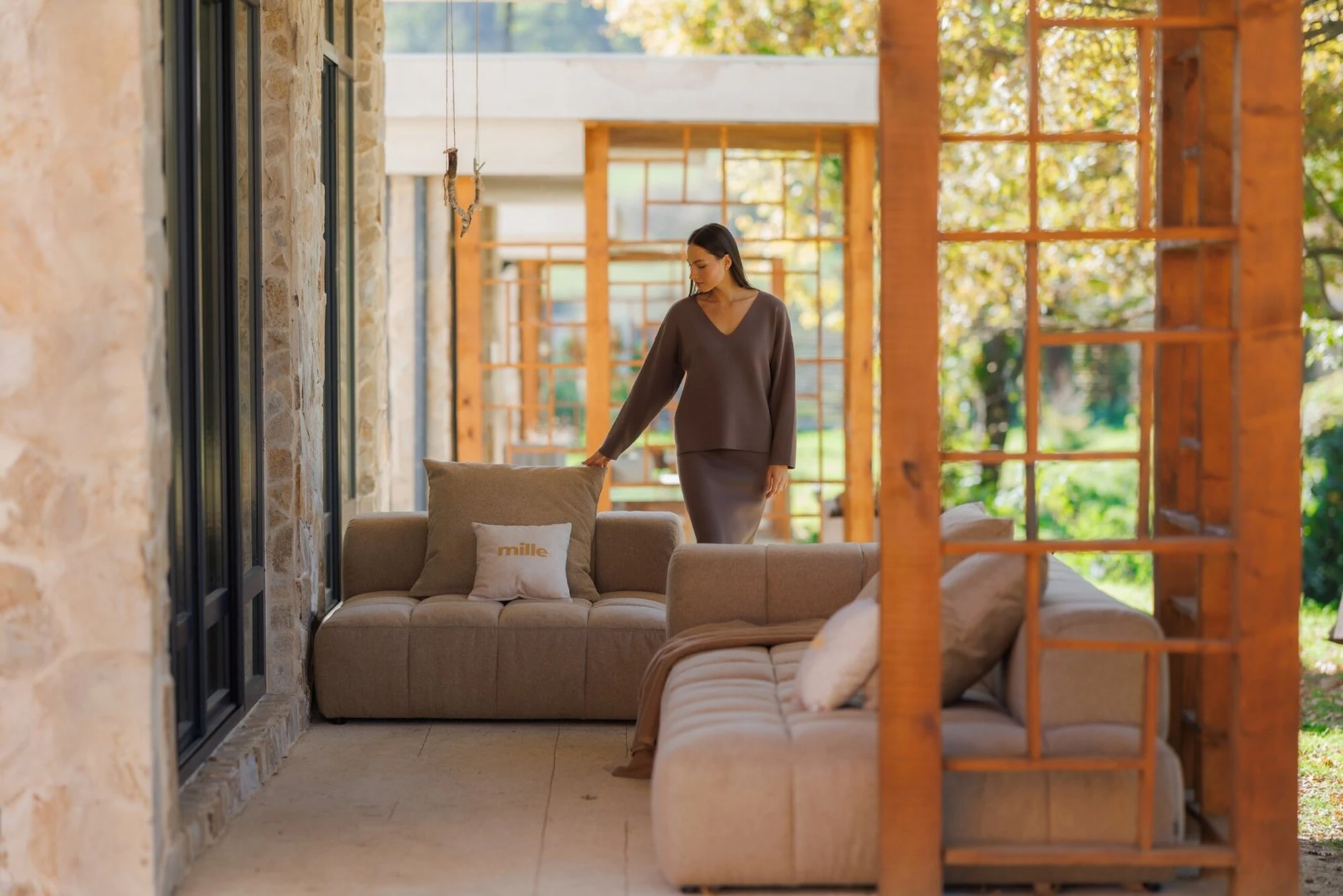 Model in mocha sweater walking by the tan Soft on a stone villa terrace