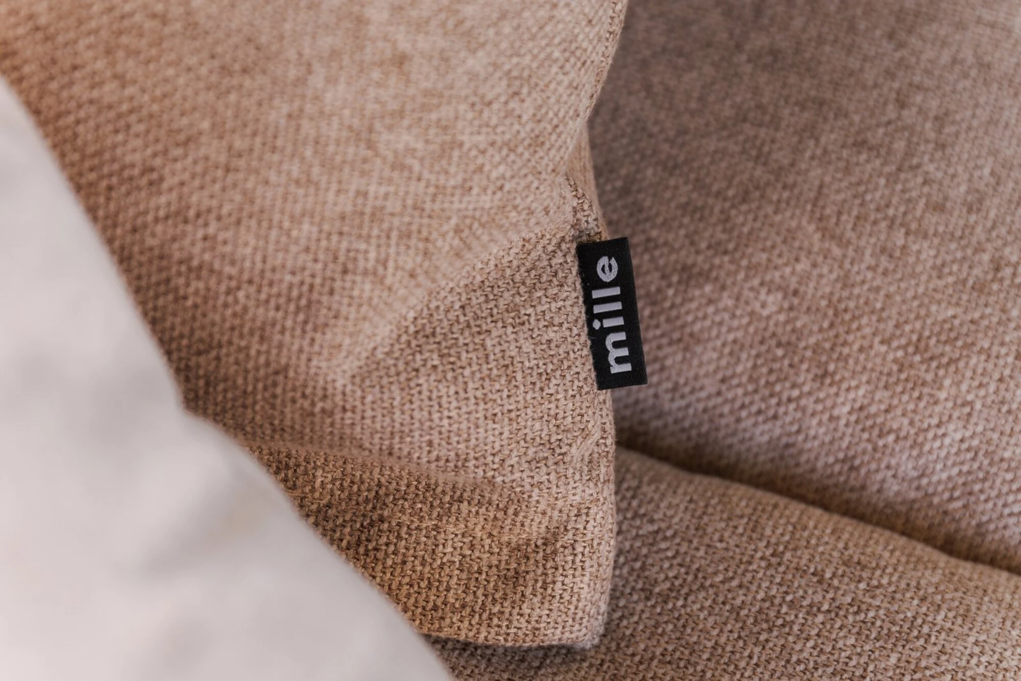 Tan Soft armrest against a rough stone-arch wall with cotton stems in a vase