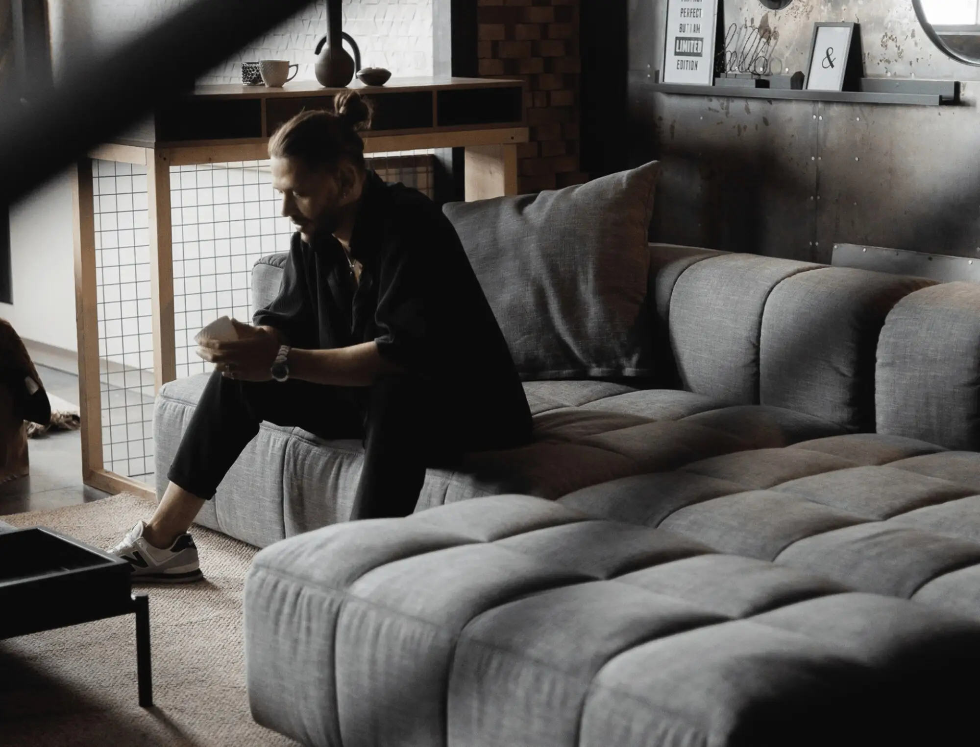 Charcoal grey Soft with a man sitting quietly on the cushions in an industrial loft