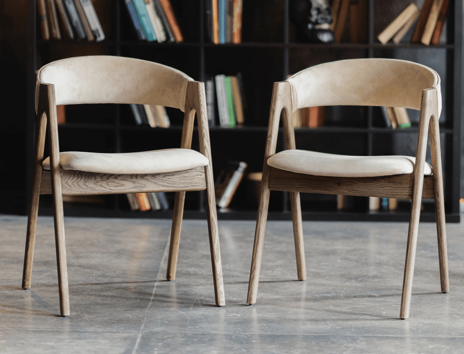A pair of light beige Bolzano Lain chairs in a library room against shelves of books