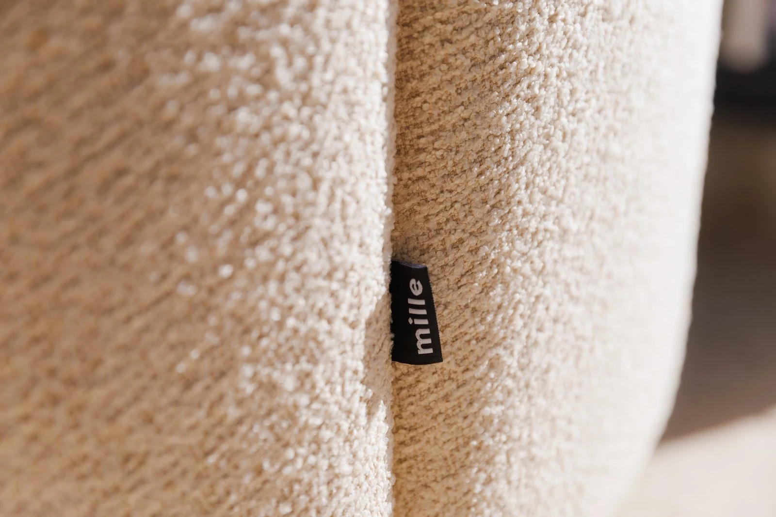 Close detail of the small Mille label sewn into the cream boucle Flora chair