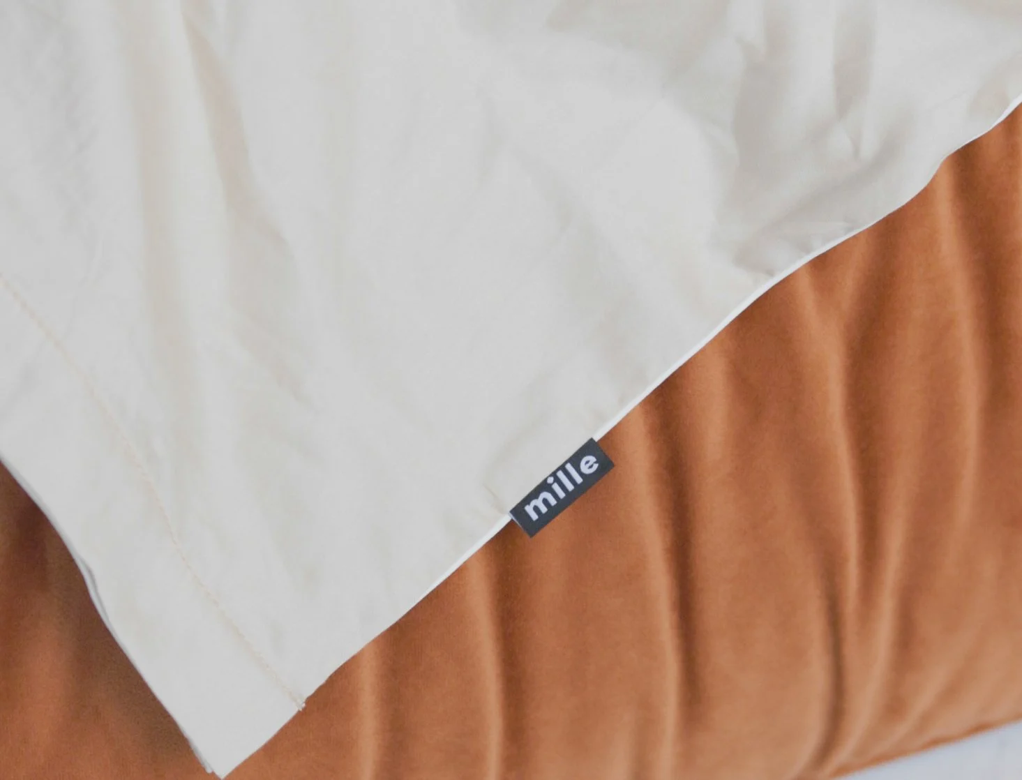Close detail of the small Mille label sewn into the seam of a burnt-orange velvet Palermo