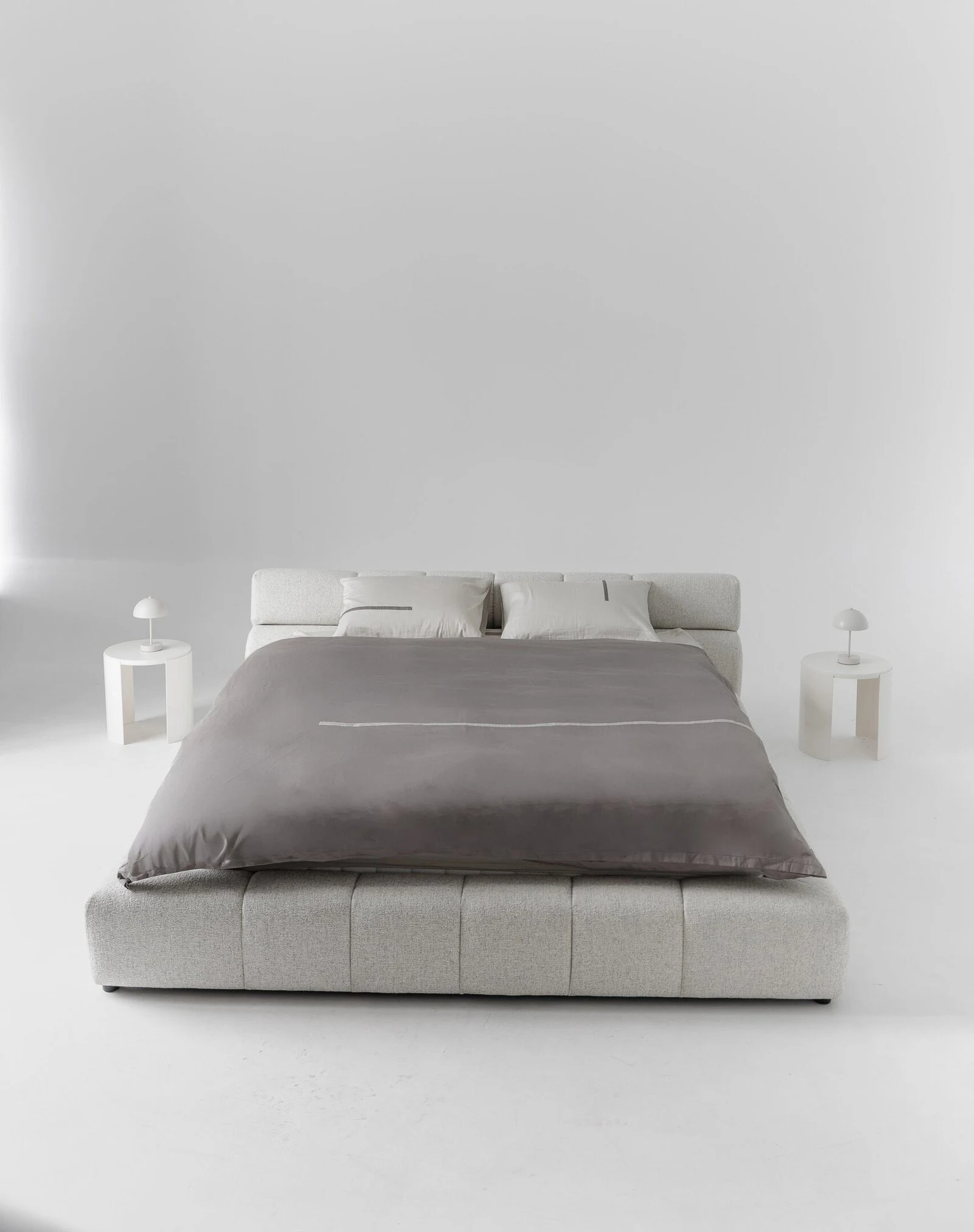 Pale heathered tweed Nao bed in an all-white studio with twin mushroom side lamps