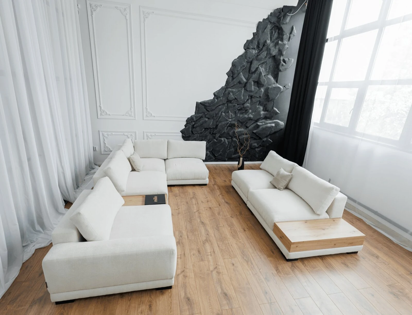 Cream Palermo L-shape against a textured stone-art wall in daylight, with sheer curtains and oak floor