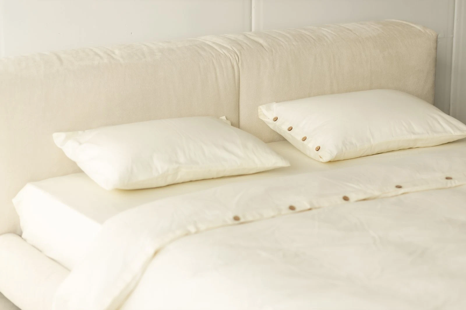 Front-on view of the Marmaris headboard showing two soft cushion blocks gently slouched against the wall, two white pillows resting in front