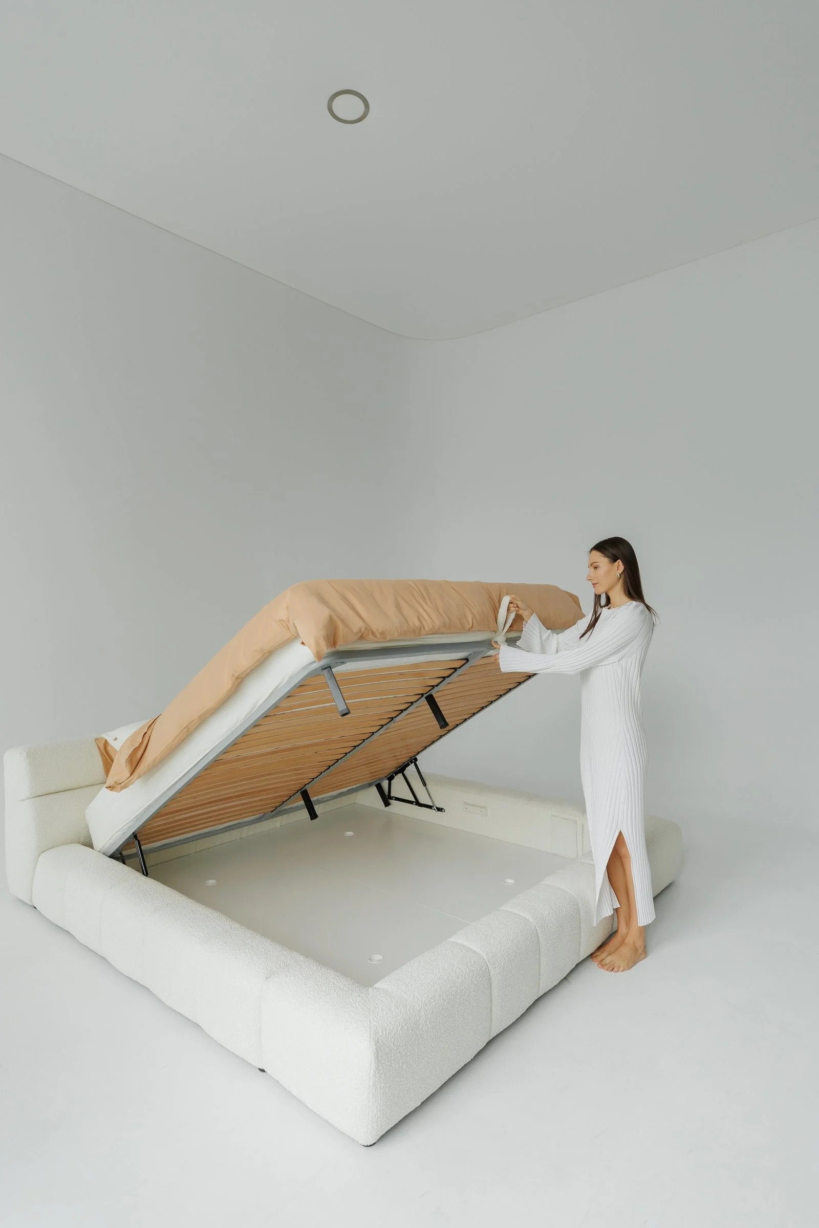 The Nao gas-lift base raised at 90 degrees, slatted wood platform visible, storage well underneath, model standing alongside