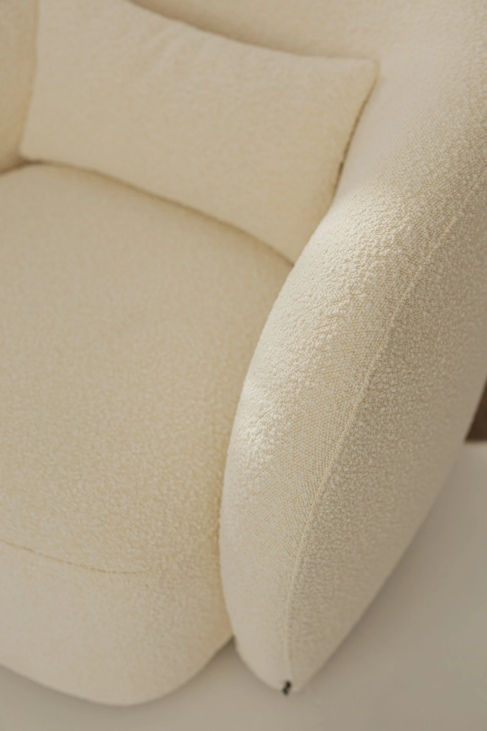 Side angle of the white boucle Nuba armchair showing the wraparound back form